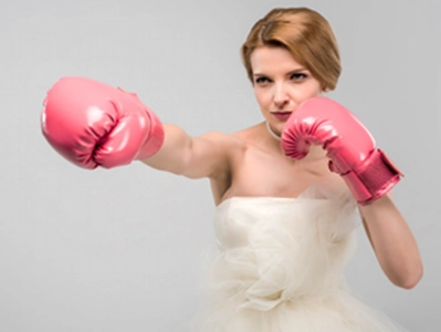 femme en robe de mariée et gants de boxe rose